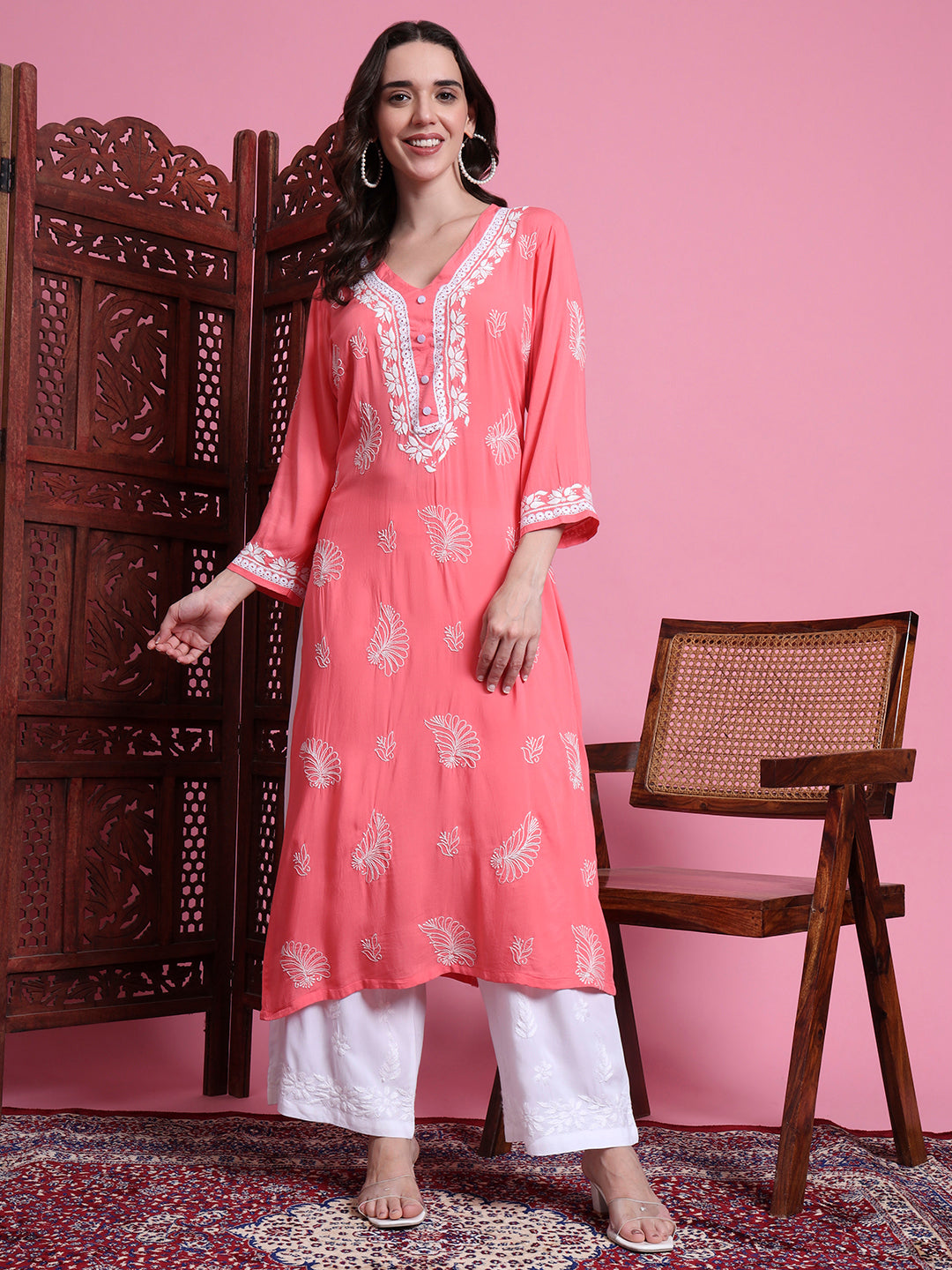 Woman wearing a coral pink kurta with white embroidery against a pink background