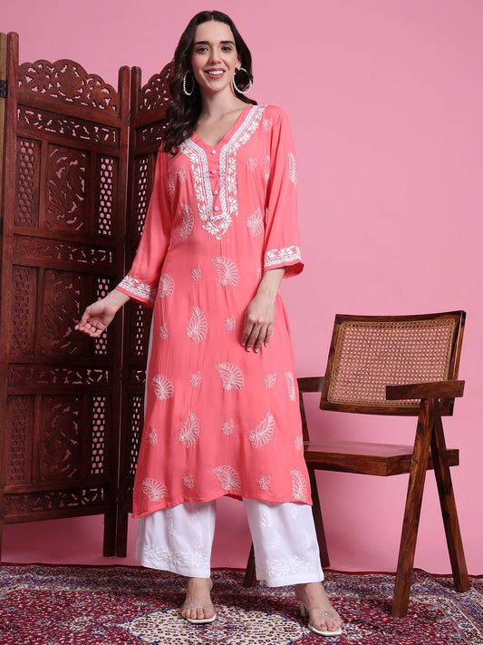 Woman wearing a coral pink kurta with white embroidery against a pink background